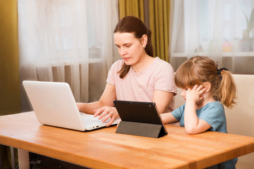 Home office. Working from home vs. Mom with two kids Work on the Internet on a laptop and kid study online at home.  quarantine. Corona Virus. 