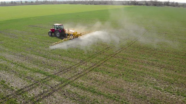 Farmer on tractor and sprayer with natural eko fertilizer with liquid manure processes field. Spring agronomic activity on agricultural land
