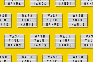 Top view flat lay pattern yellow background. Lightbox with wash your hands text. Covid-19 pandemic
