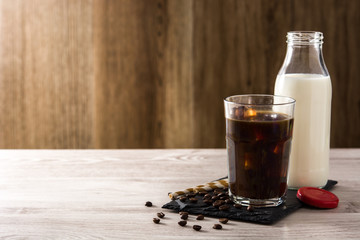 Iced coffee or caffe latte in tall glass on wooden table. Copy space