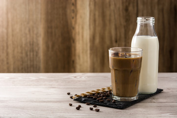 Iced coffee or caffe latte in a tall glass on wooden table. Copy space