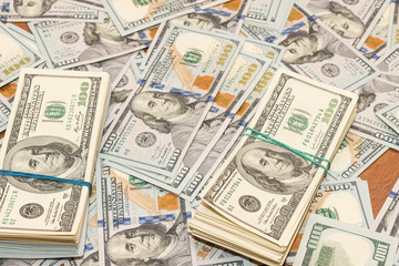 Many hundred dollar bills on wooden table background texture. bundles of money scattered on the office desk. wealth and income concept