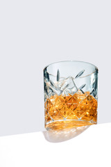 Old Fashioned Whiskey is contained in a crystal lowball glass and isolated on a table edge. The showy illustrative picture is made on the gray backdrop.