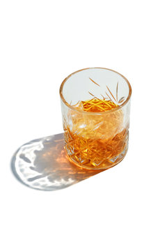 Old Fashioned Whiskey is contained in a crystal lowball glass with ice cubes. The showy illustrative picture is made on the white backdrop.