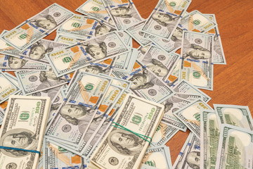 Fototapeta na wymiar Many hundred dollar bills on wooden table background texture. bundles of money scattered on the office desk. wealth and income concept
