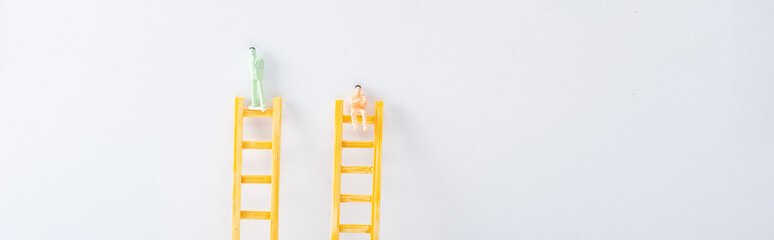 Panoramic shot of two people figures on ladders on white background, concept of equality rights