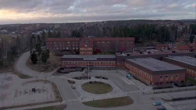 Orbiting drone footage showing an empty parking lot belonging to a closed down hospital in Fagersta, Sweden on an overcast day in March. Filmed in realtime at 4K.