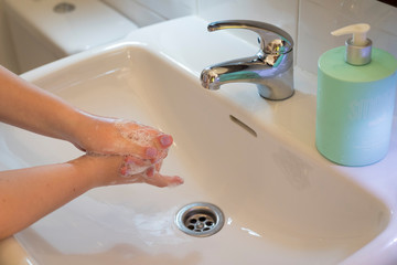 Girl's hand wash with water in the bathroom to protect herself from bacteria corona virus