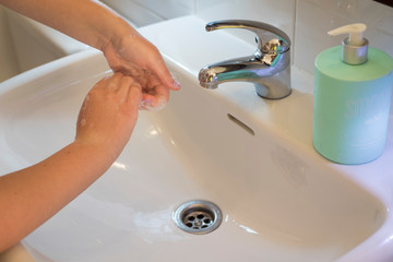 Girl's hand wash with water in the bathroom to protect herself from bacteria corona virus