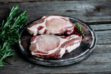 Raw meat on a cutting board on the kitchen table. Pork steak. Country style.
