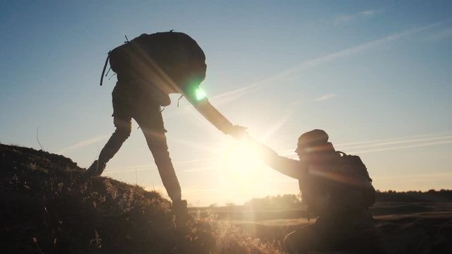 teamwork two men help helping hand business travel silhouette concept. lifestyle two tourists lends a helping hand climb the cliffs mountains. people climbers climb to the top teamwork overcoming