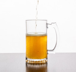 Beer is poured into a glass glass on a white background.