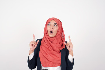 Portrait of beautiful elegant woman over isolated background being amazed and surprised looking and pointing up with fingers showing something strange.