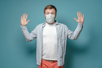 Frightened man in a medical mask wants to avoid the spread of the virus when touched and raises...