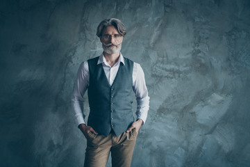 Photo of aged macho business man standing calm not smiling serious wear specs office white shirt waistcoat trousers isolated over concrete grey color wall background