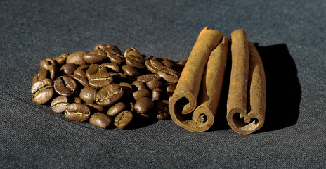 Cinnamon and coffee on a dark cloth in natural sunlight.