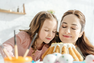 selective focus of happy mother and daughter smelling easter cake