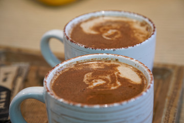 Cup of coffee with heart pattern in a white cup on wooden background