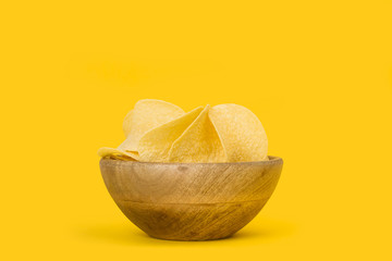 Patatas fritas dentro de un cuenco de madera sobre fondo amarillo aislado y brillante. Vista de...