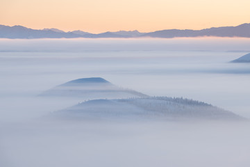 winter landscape with mountains and fog. Beautiful sunrise over the mountains in foggy morning....