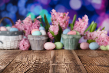 Easter background. Rustic wooden table. Tulips and spring flowers. Easter eggs. Pastel colors bokeh. 