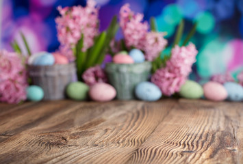 Easter background. Rustic wooden table. Tulips and spring flowers. Easter eggs. Pastel colors bokeh. 