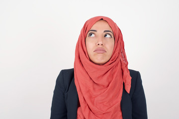 Gloomy, bored girl frowns face looking up, being upset with so much talking hands down, feels tired and wants to leave. Angry sullen woman standing indoors.