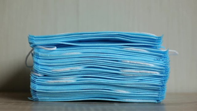 People takes a disposable sterile mask from a large stack