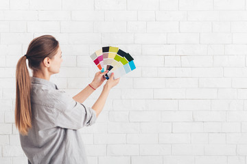 Young woman choosing color of walls in new room