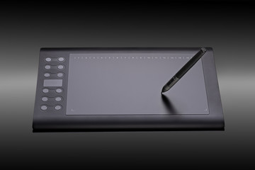 Digital graphic tablet with pen for illustrators and designers on a black background. Modern black graphic tablet for drawing closeup