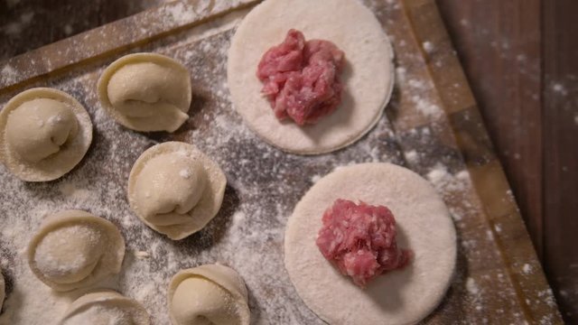 Ready to be cooked dumplings lying in wooden board in an kitchen. Left to right top view pan real time close up shot. Closeup of making dumpling food. Rows of prepared dumplings. Dumplings closeup