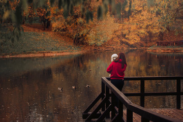 woman standing by the pond with white poodle dog