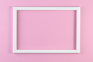 Wooden white frame on pink pastel color background. Minimal creative concept.