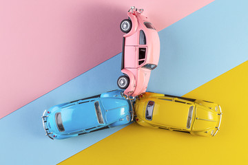 Toy cars in accident on a pastel colorful background. Three car accident scene, Car crash insurance. Racing cars on the race track.