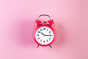 Red vintage alarm clock on light pink color background. Alarm clock with place for text. Time...