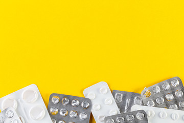 A pile Used blister packs of pills on yellow background. Medical blisters packs opened and empty without pills top view. Medical and healthcare concept.