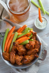 Buffalo chicken wings with vegetables and a glass of beer
