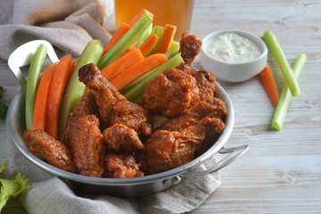 Buffalo chicken wings with vegetables and a glass of beer