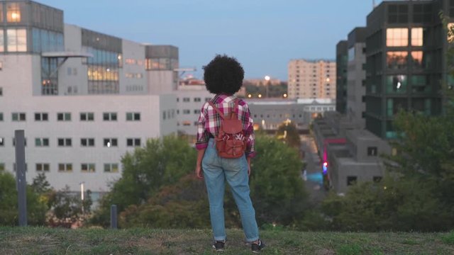 Rear view of young woman with backpack enjoying view to the city