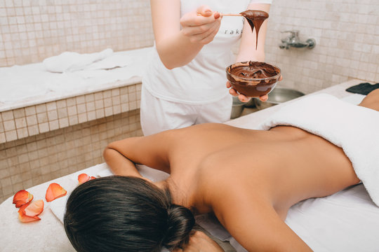 Chocolate wrap in the spa. Young woman getting a chocolate mask on her body to moisturize her skin