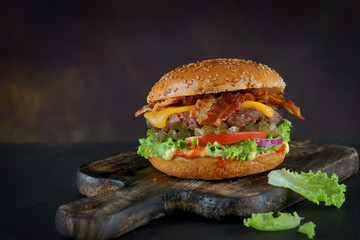 Burger with bacon and cheese on a dark background