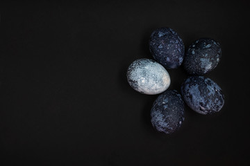 Painted cosmic dark blue eggs with white dots on black background. Happy easter concept. Copy space