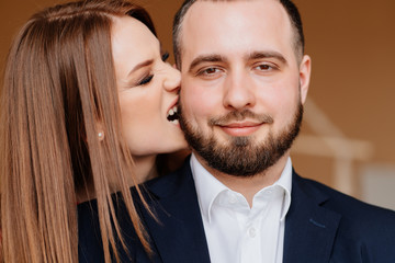 girl in red dress bites on cheek man in suit and 