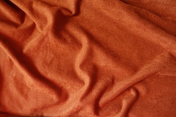 Fototapeta na wymiar Draped bright reddish orange artificial suede fabric