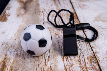 Football with whistle on old white wood