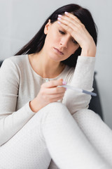 selective focus of displeased woman holding pregnancy test with negative result