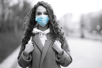 Black and white foto of girl in protective sterile medical mask on the street. Woman, wear face...