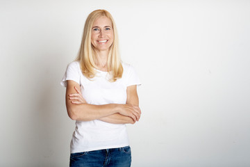 Emotional middle-aged woman smiling at grey studio