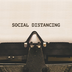 Social Distancing, written on vintage type writer machine from 1920s closeup with paper