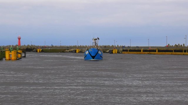 Handheld shot of Blue Fishing Boat Entering Harbor in Kolobrzeg, Poland.